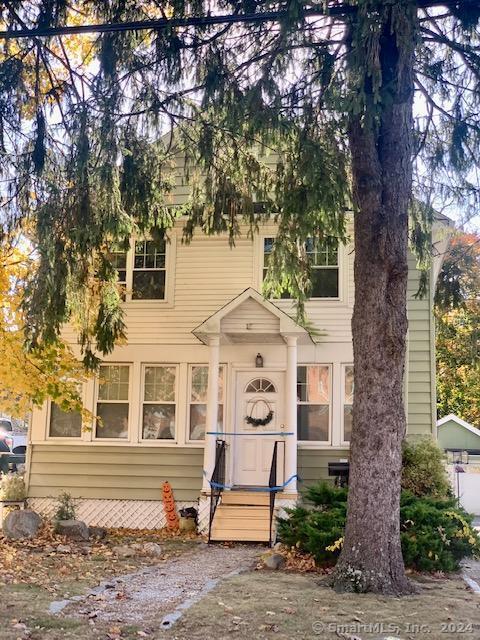 a front view of a house with a tree