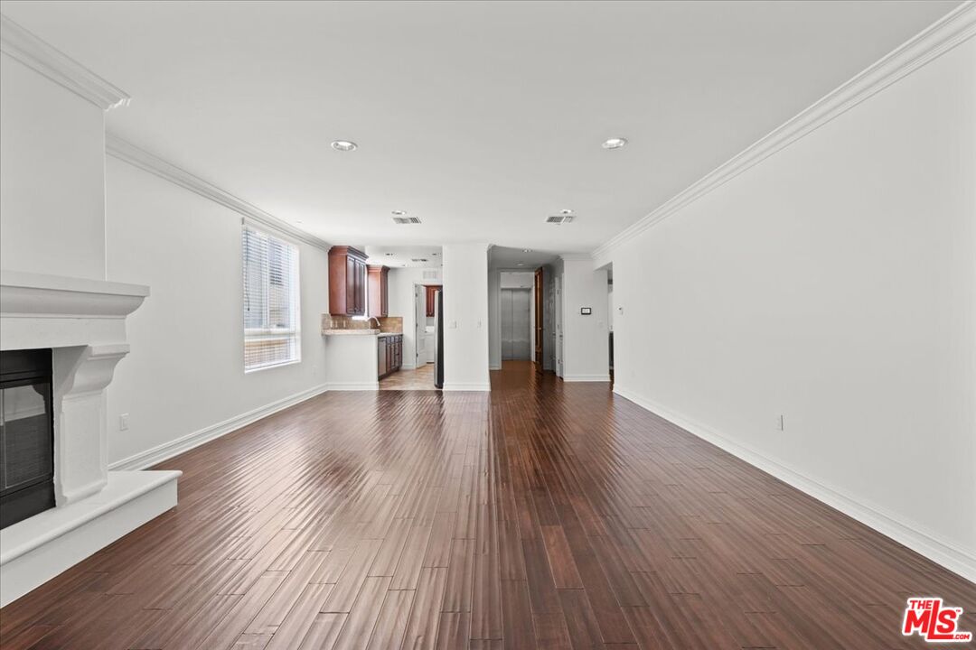 a view of a livingroom with wooden floor and a kitchen