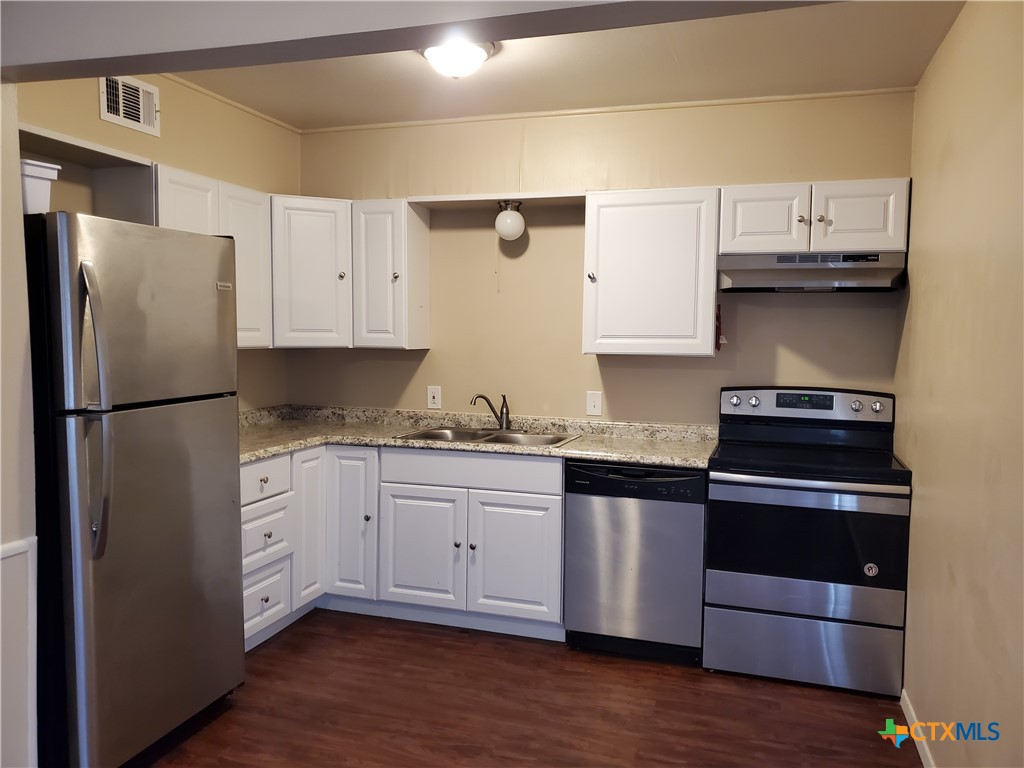 a kitchen with stainless steel appliances granite countertop a refrigerator and a stove top oven