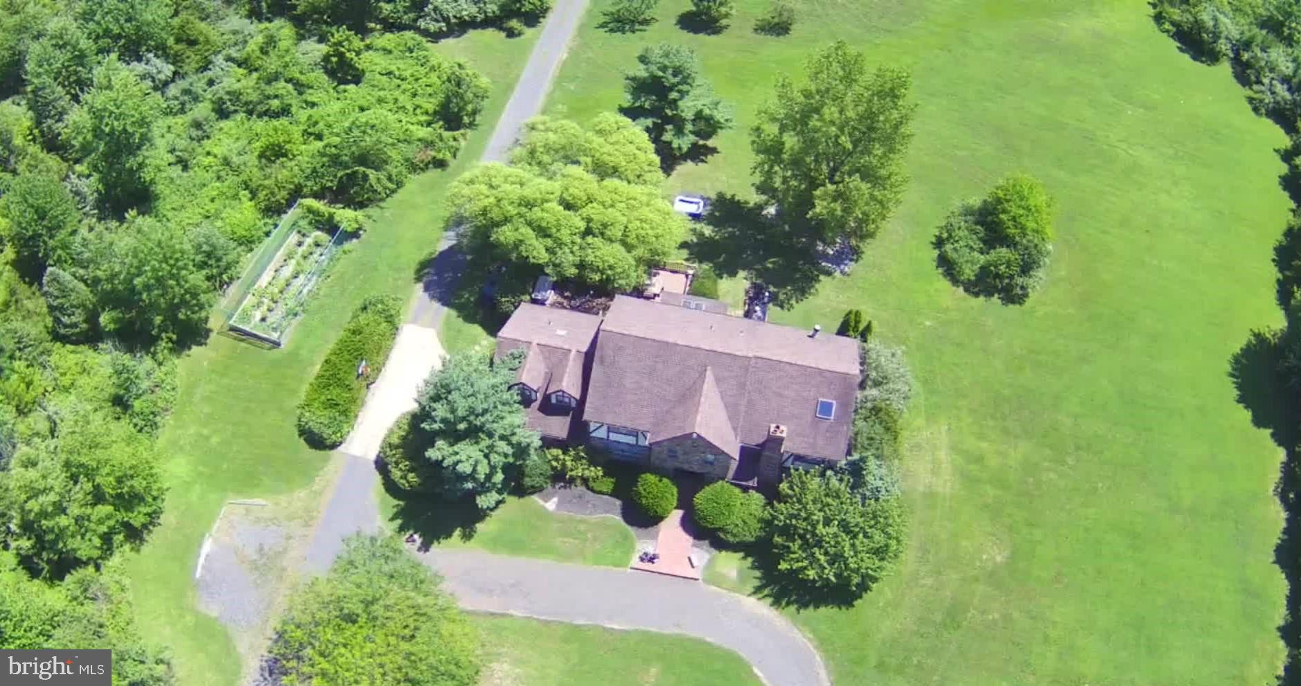 an aerial view of a house with a yard and trees all around