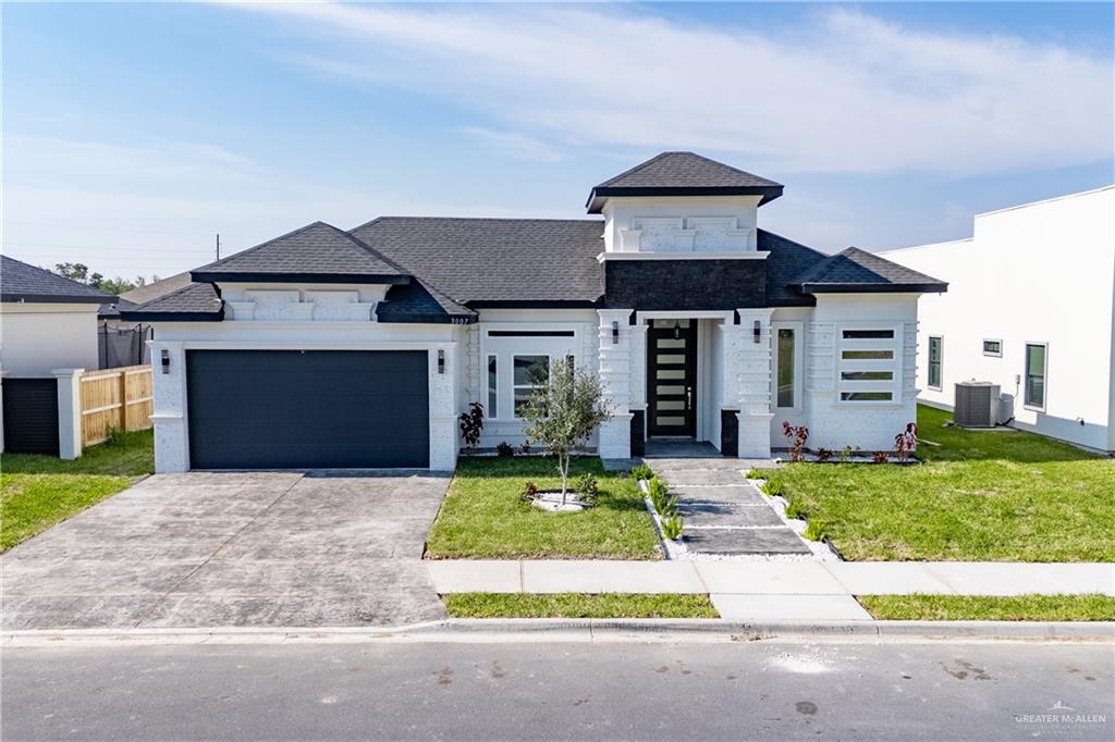 View of front of house featuring a garage, a front lawn, and central air condition unit