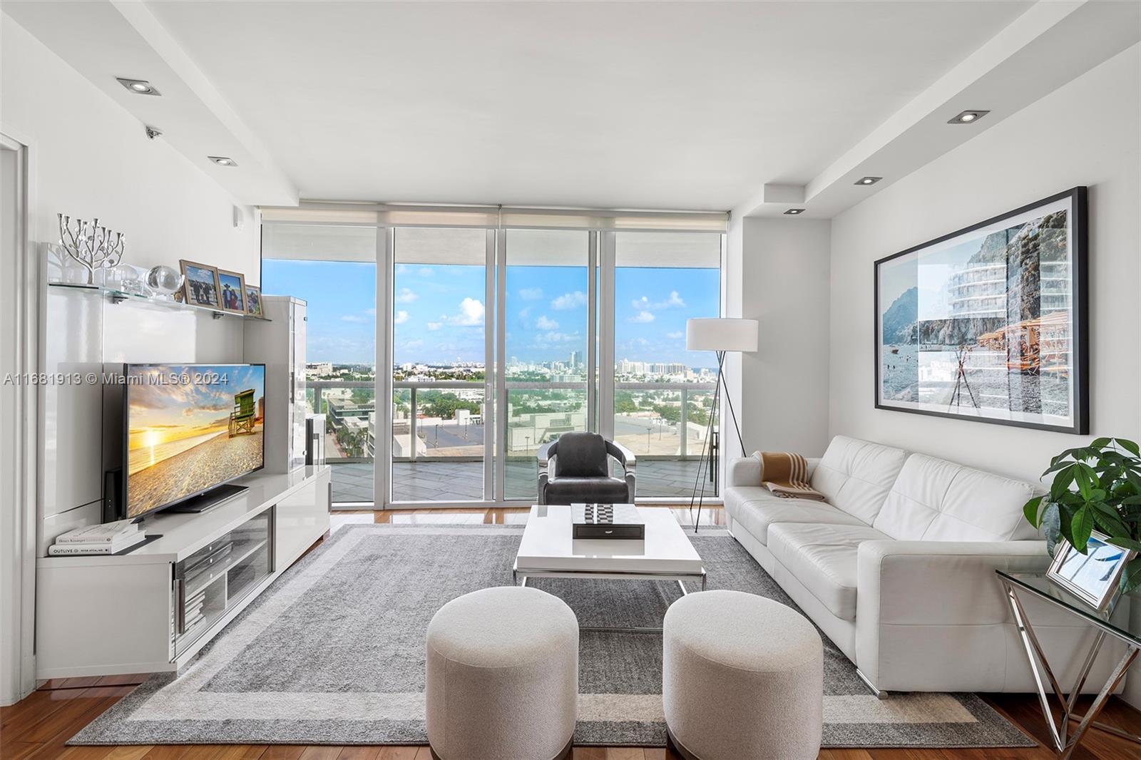 a living room with furniture a flat screen tv and a floor to ceiling window