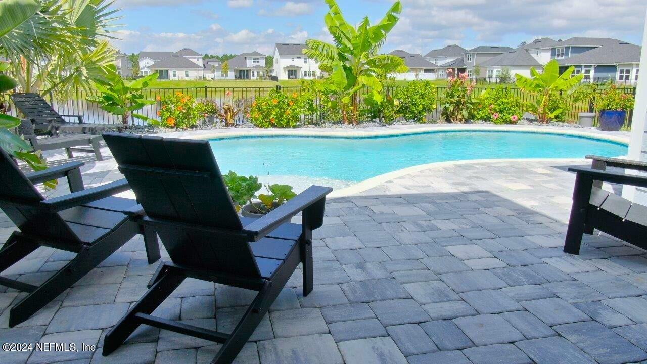 a view of a chairs and table in patio with swimming pool