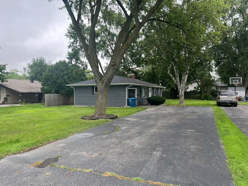 a view of a house with a yard and large tree