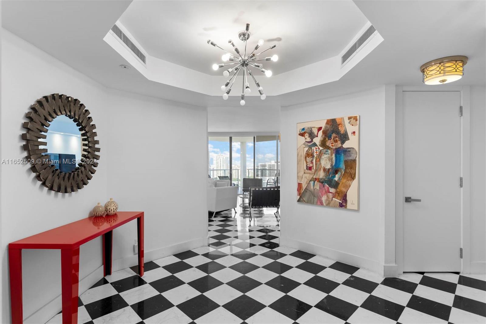 a living room with a black white checkered floor with a gaming machine and dining table