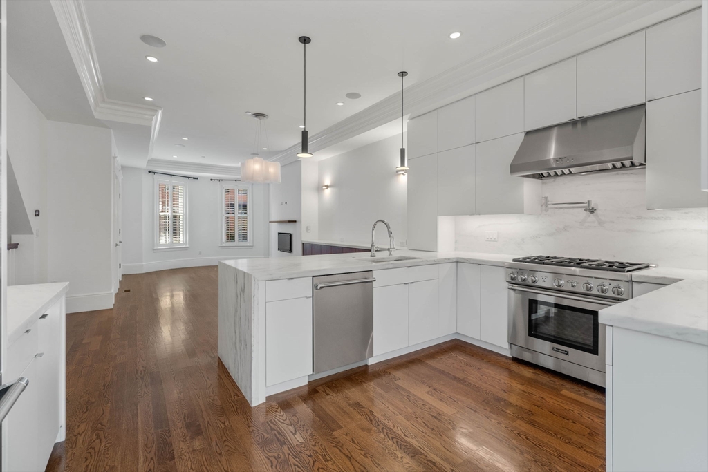 a kitchen with a stove a sink and wooden floor