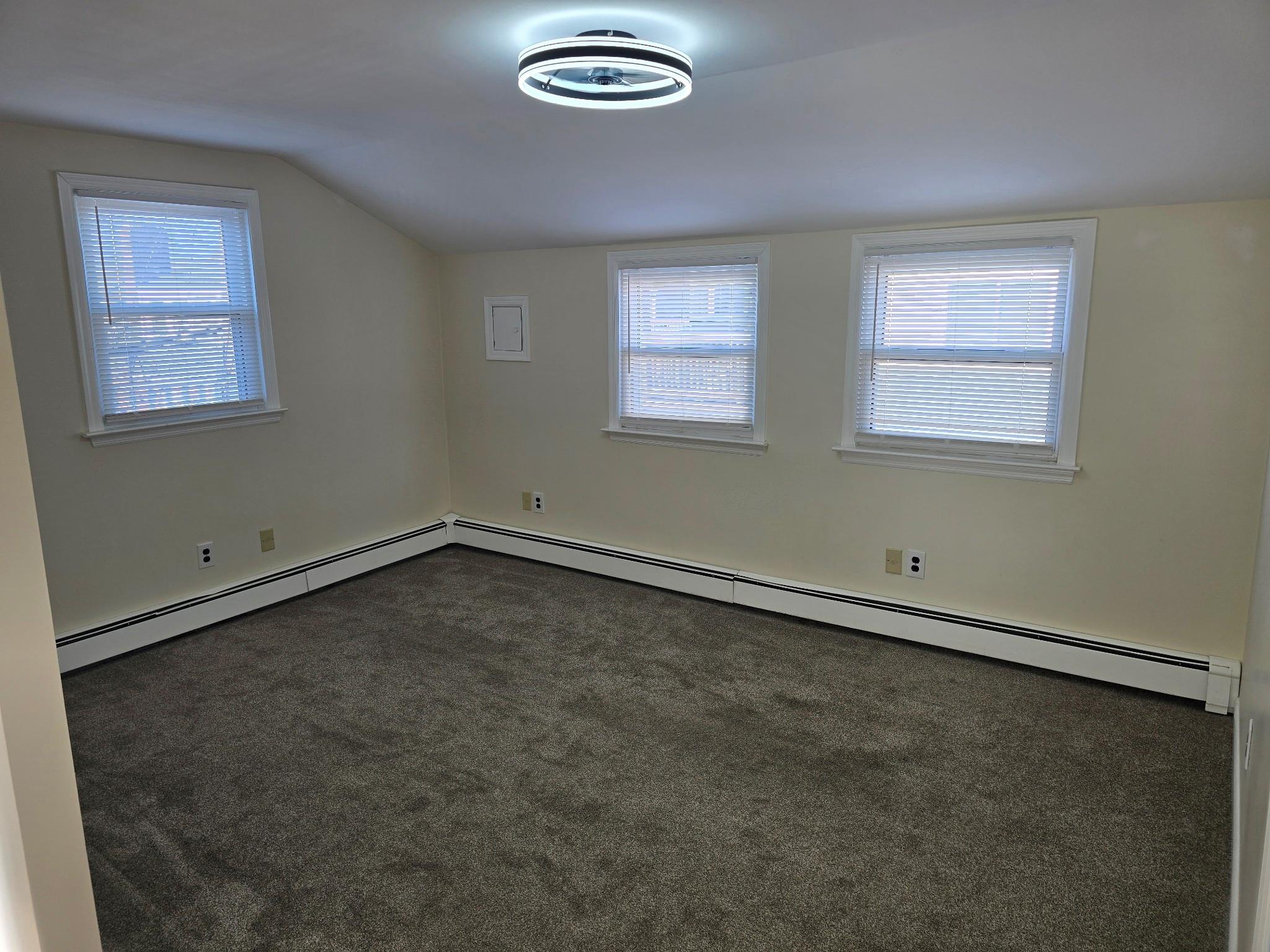 Bonus room featuring dark carpet, lofted ceiling, and a baseboard heating unit