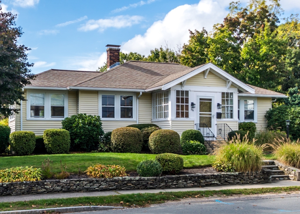 a front view of a house with a yard and potted plants