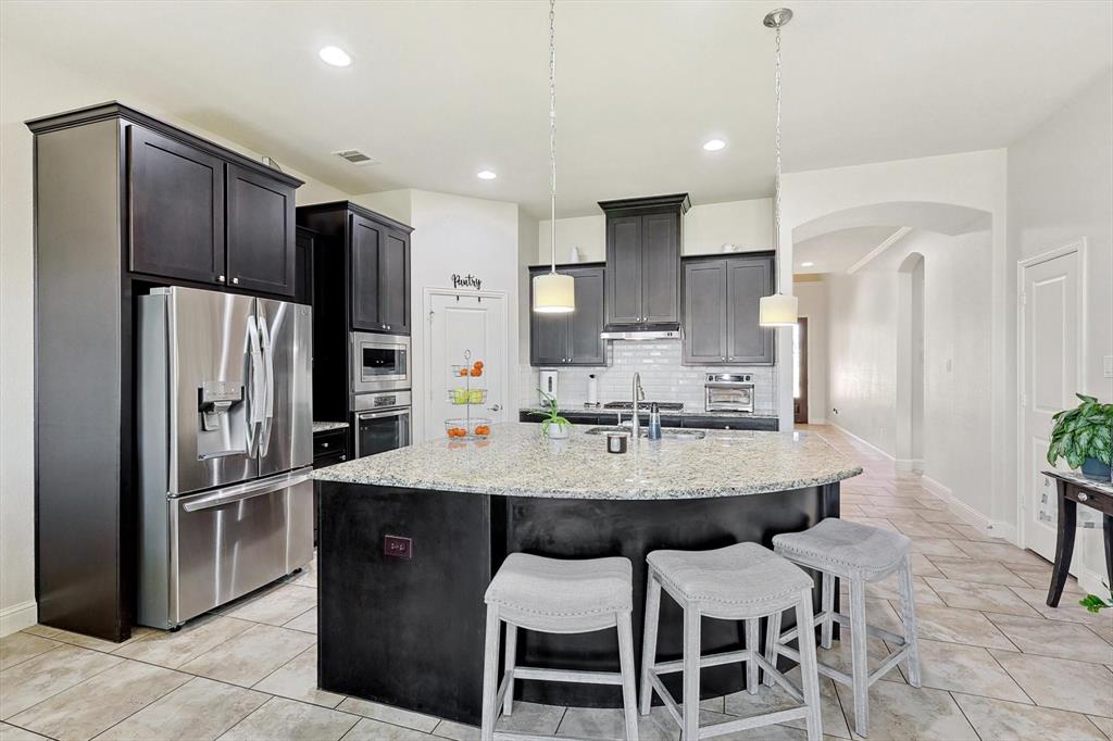 a kitchen with stainless steel appliances a dining table chairs refrigerator and microwave