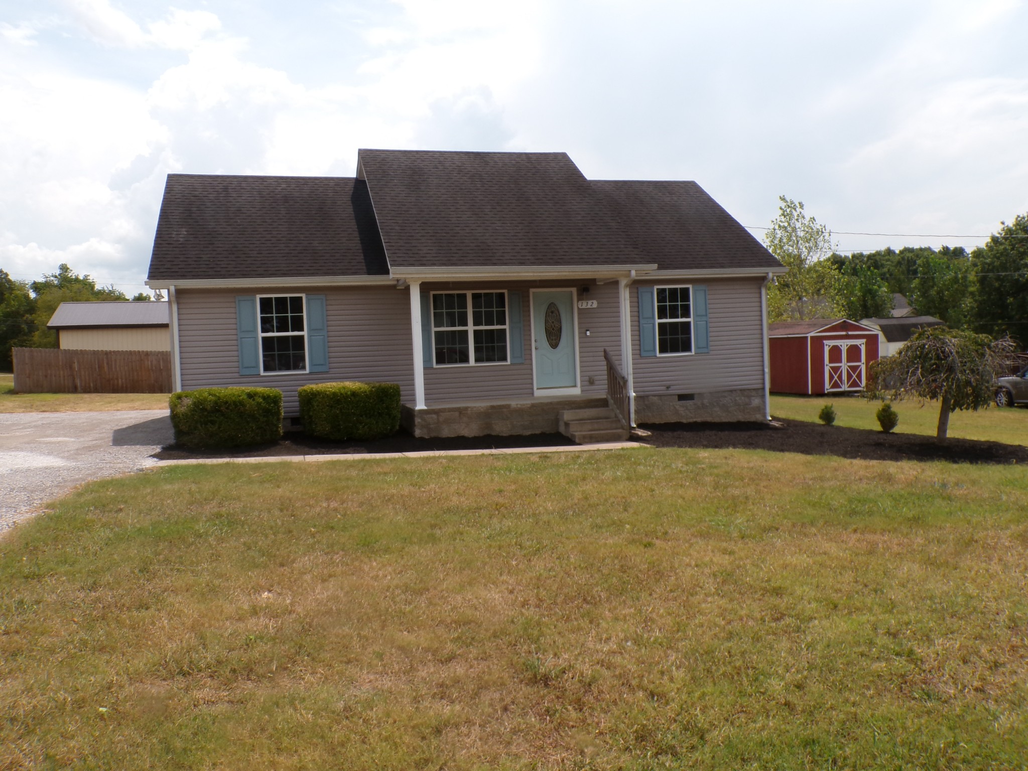 a front view of house with yard and trees in the background