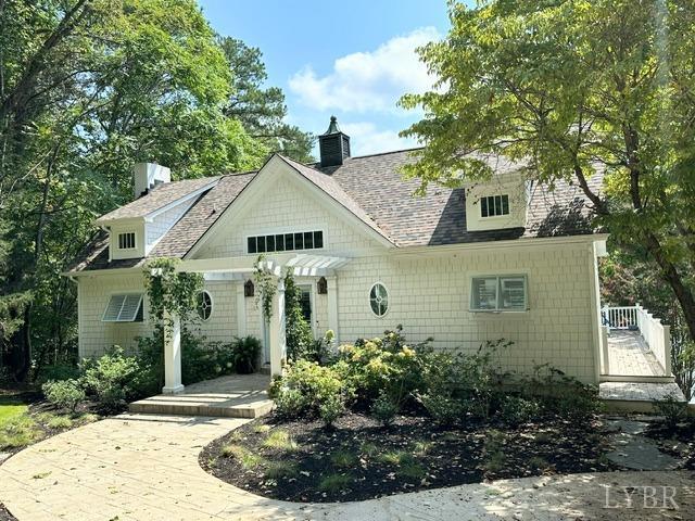 a view of a white house next to a yard with plants and trees