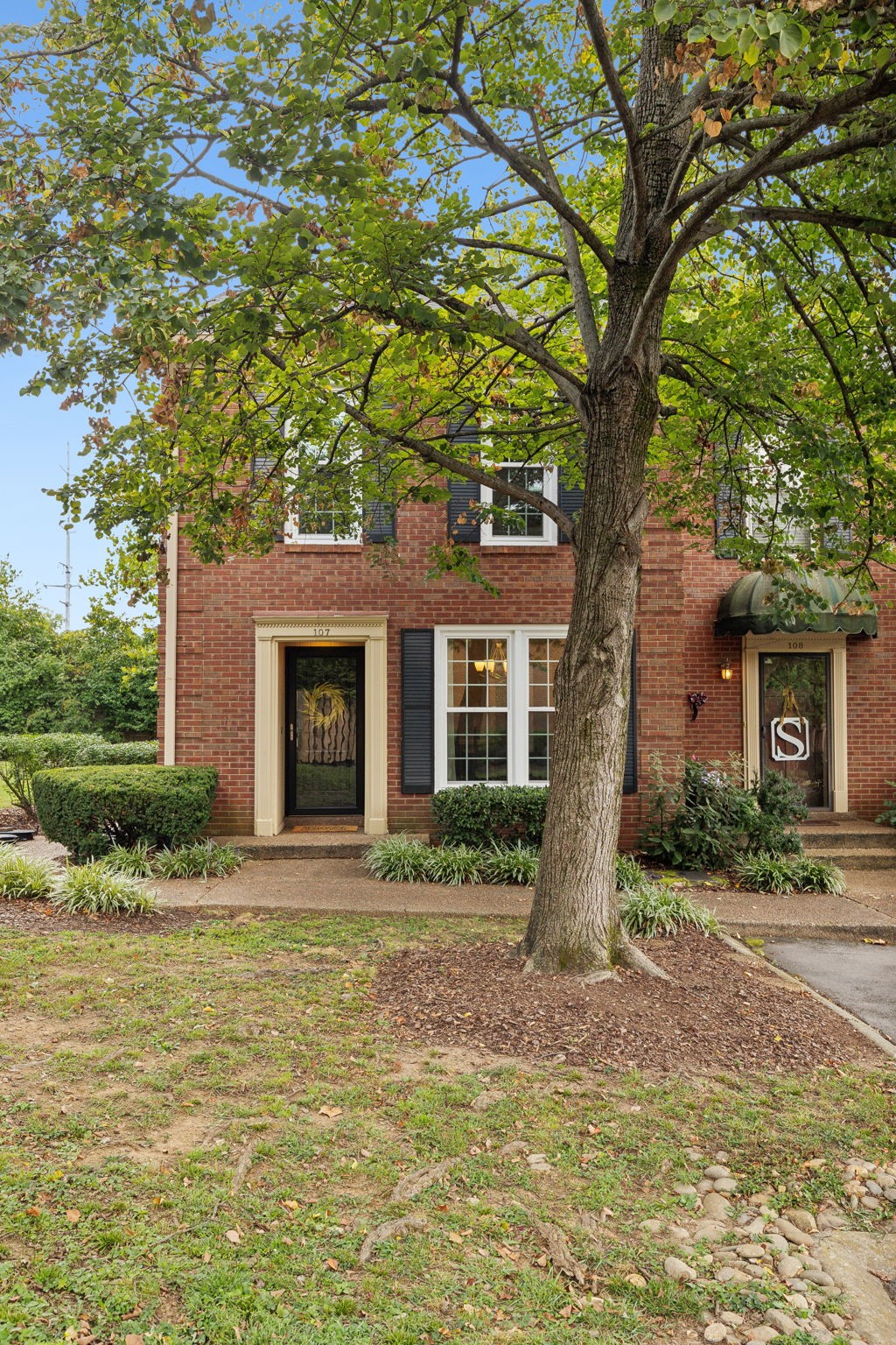 a front view of a house with garden and trees