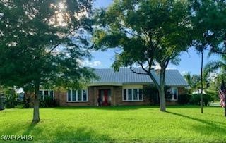 a view of a brick house with a big yard and large trees