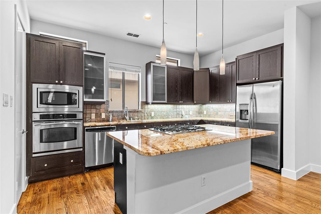 a kitchen with stainless steel appliances granite countertop a sink a stove and a refrigerator