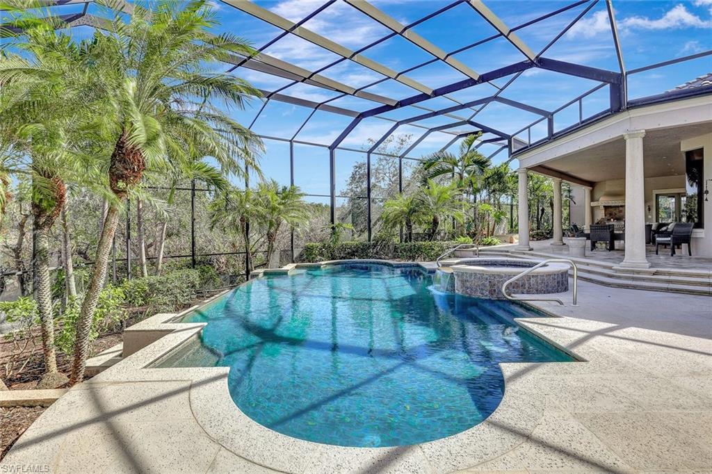 View of swimming pool with glass enclosure, a patio area, and an in ground hot tub