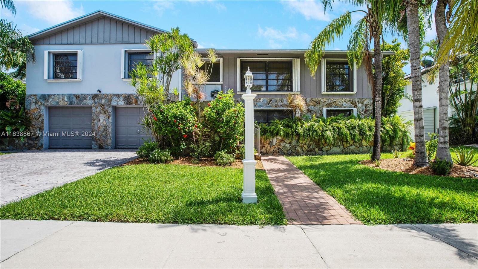 a front view of a house with a yard and potted plants