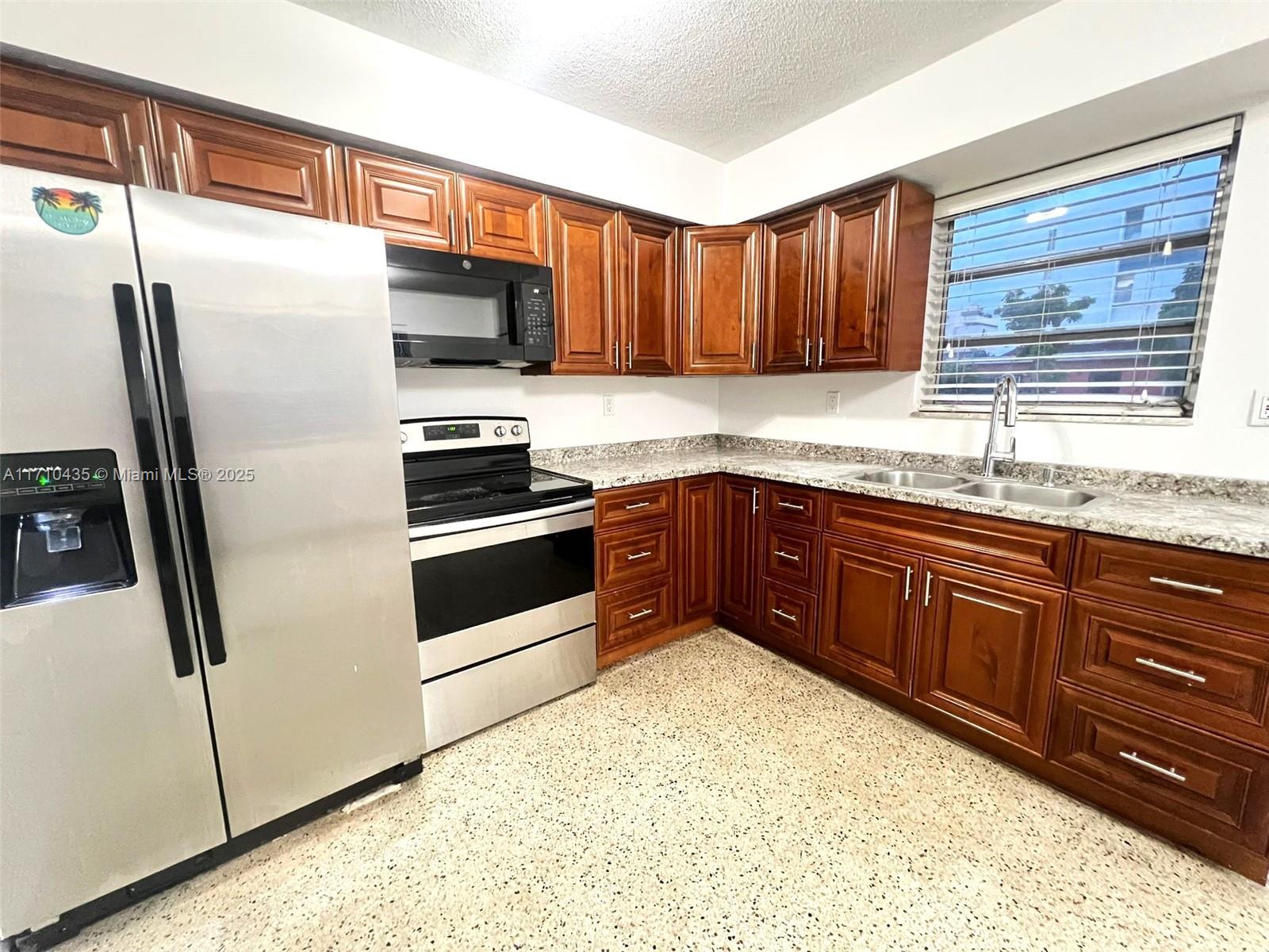 a kitchen with stainless steel appliances granite countertop a stove a sink and a refrigerator