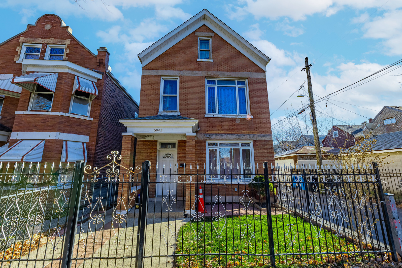 a view of a brick house with many windows and a yard with plants