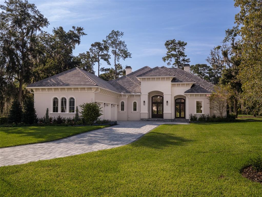 a view of a white house in front of a big yard with large trees