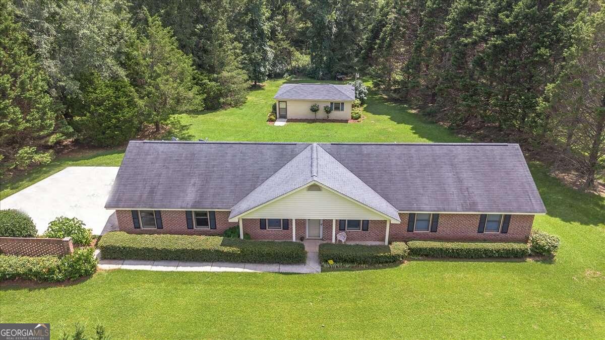 a aerial view of a house next to a big yard and large trees