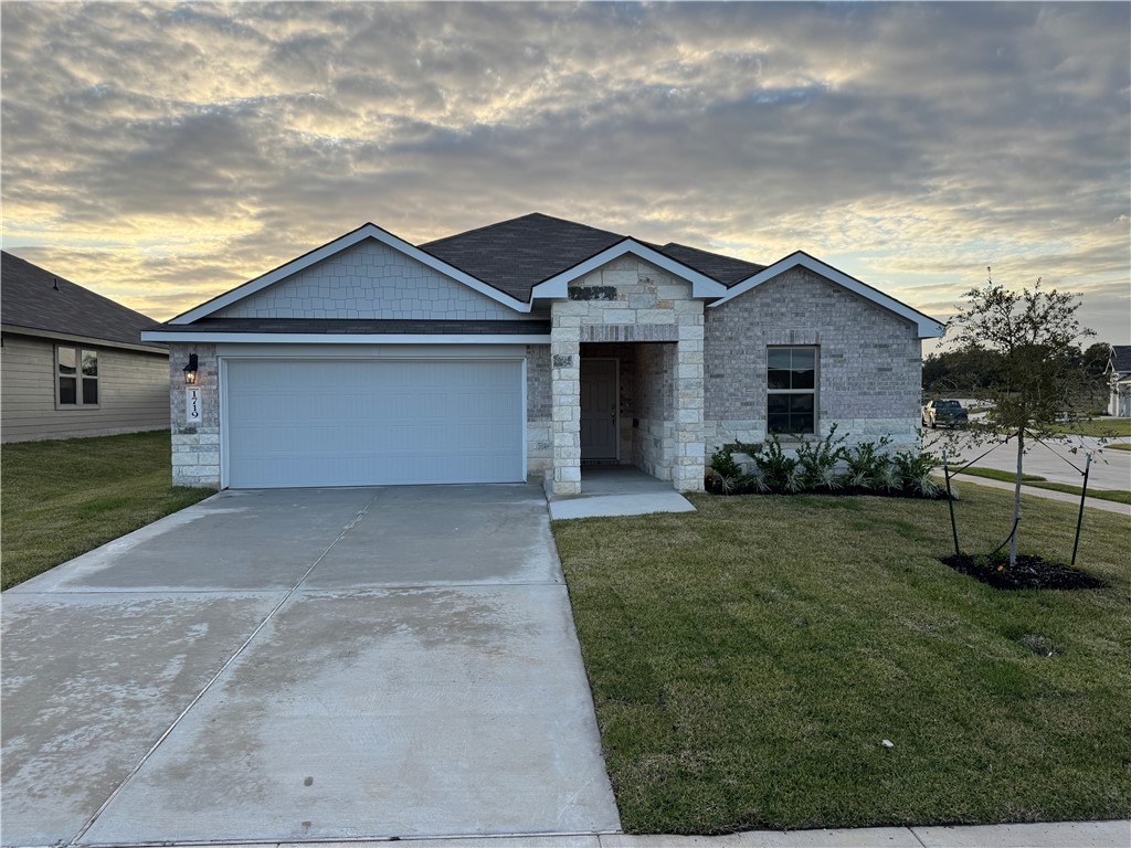 View of front of home featuring a garage and a law