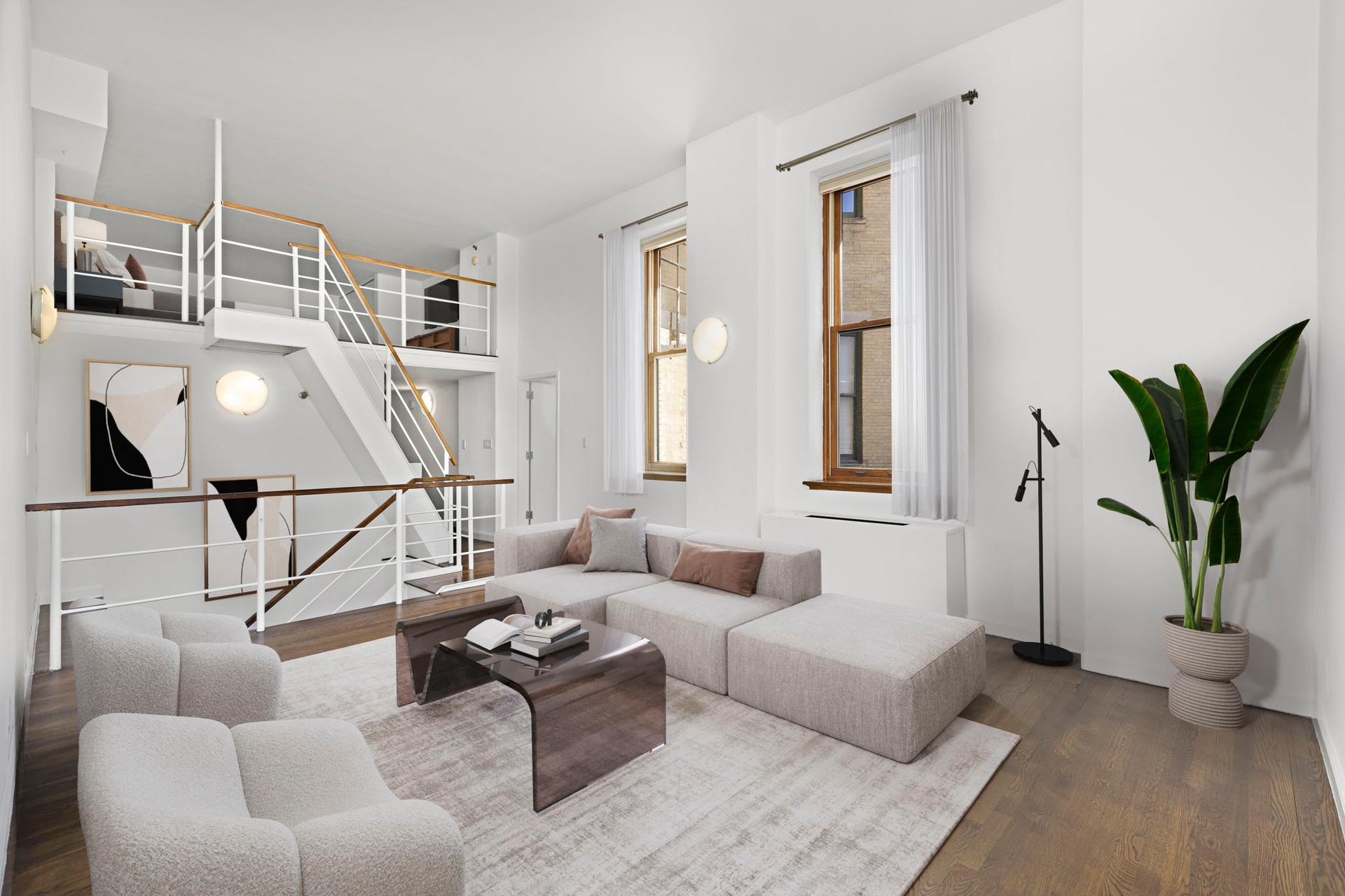 a living room with furniture a wooden floor and a potted plant