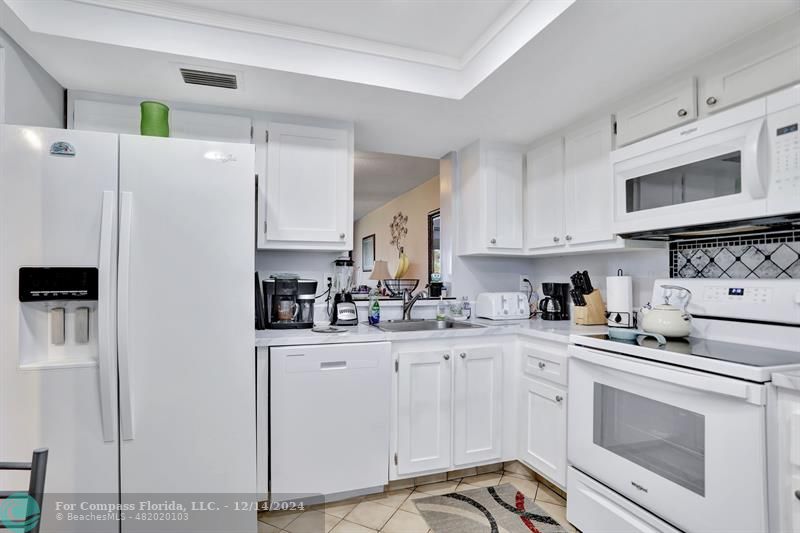 a kitchen with white cabinets and white appliances