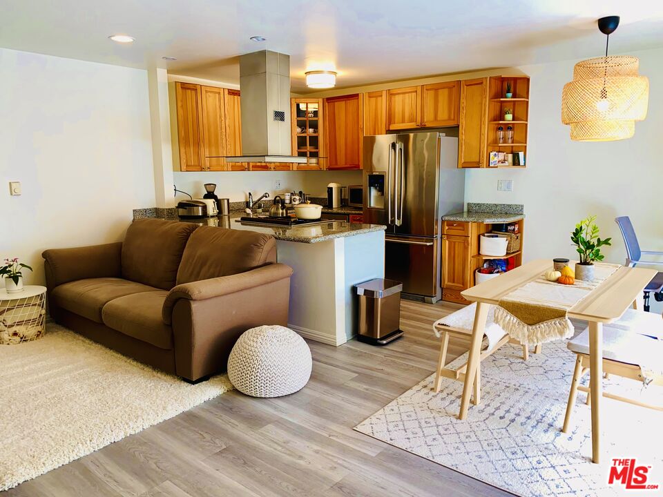 a living room with stainless steel appliances furniture a rug and a kitchen view