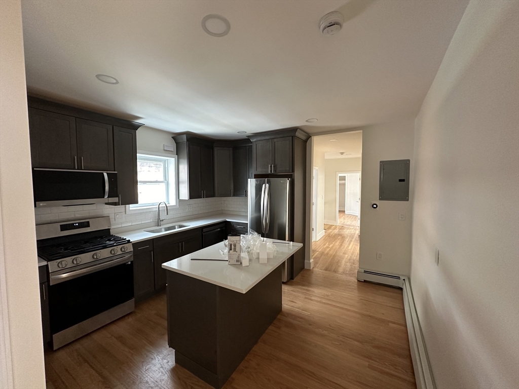 a kitchen with a refrigerator a sink and wooden floor