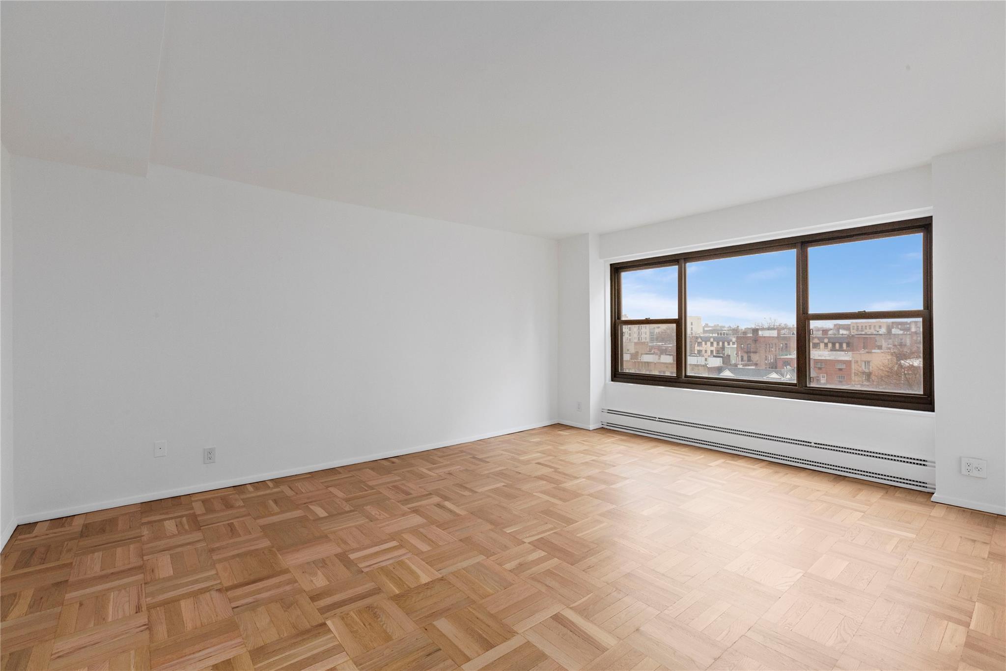 Unfurnished room with light parquet floors and a baseboard heating unit