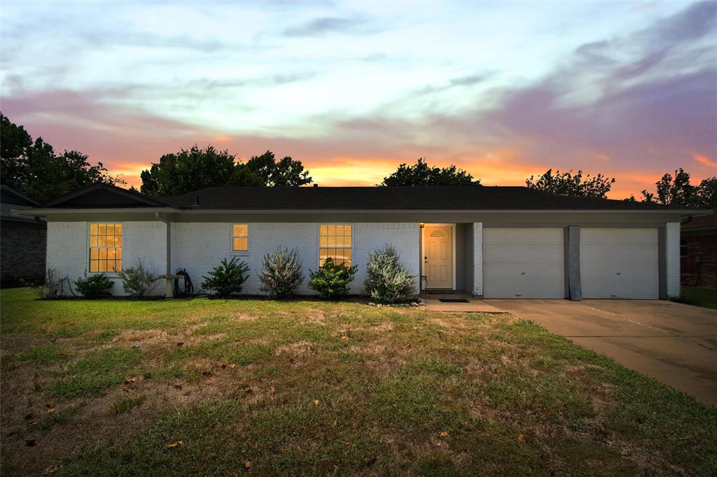 a front view of house with yard and trees in the background