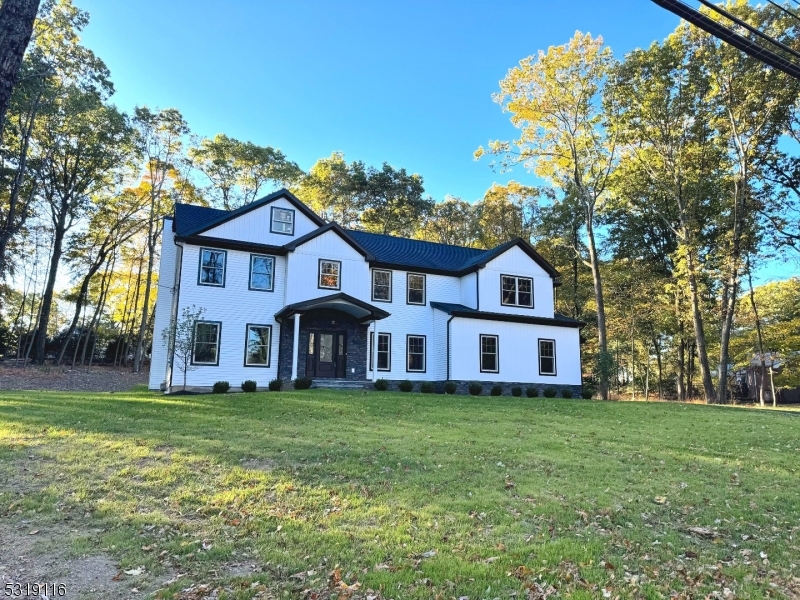 a view of a house next to a big yard and large trees