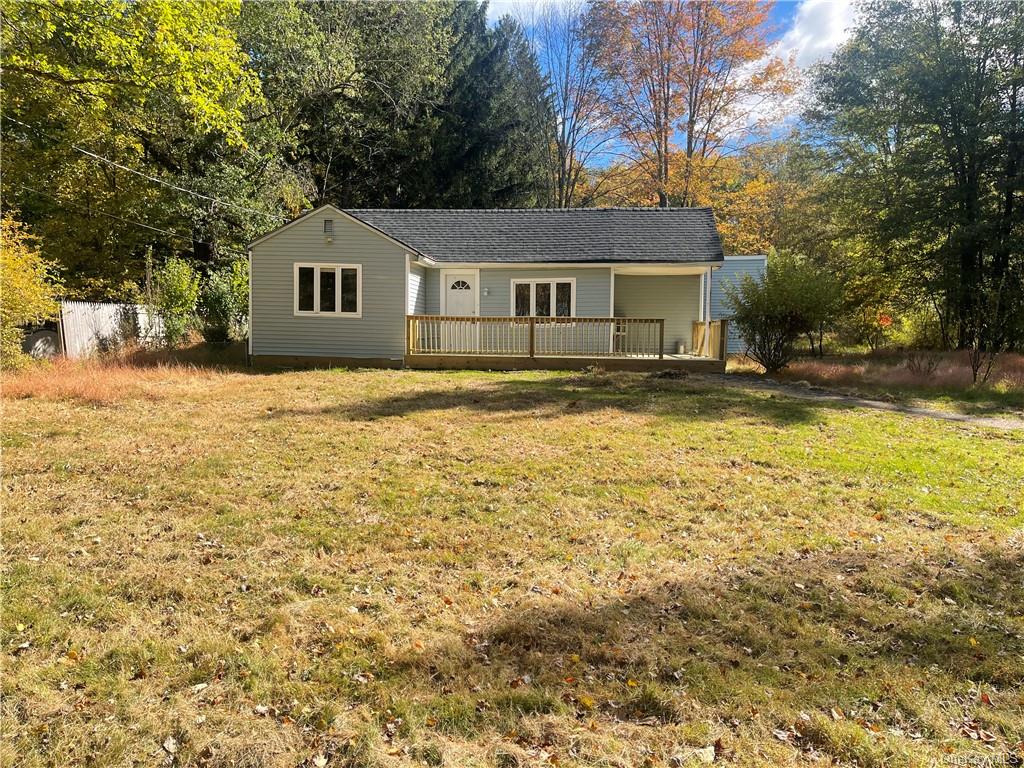 Ranch-style house featuring a wooden deck and a front lawn