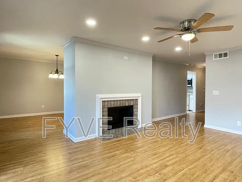 a view of an empty room with wooden floor and a fireplace