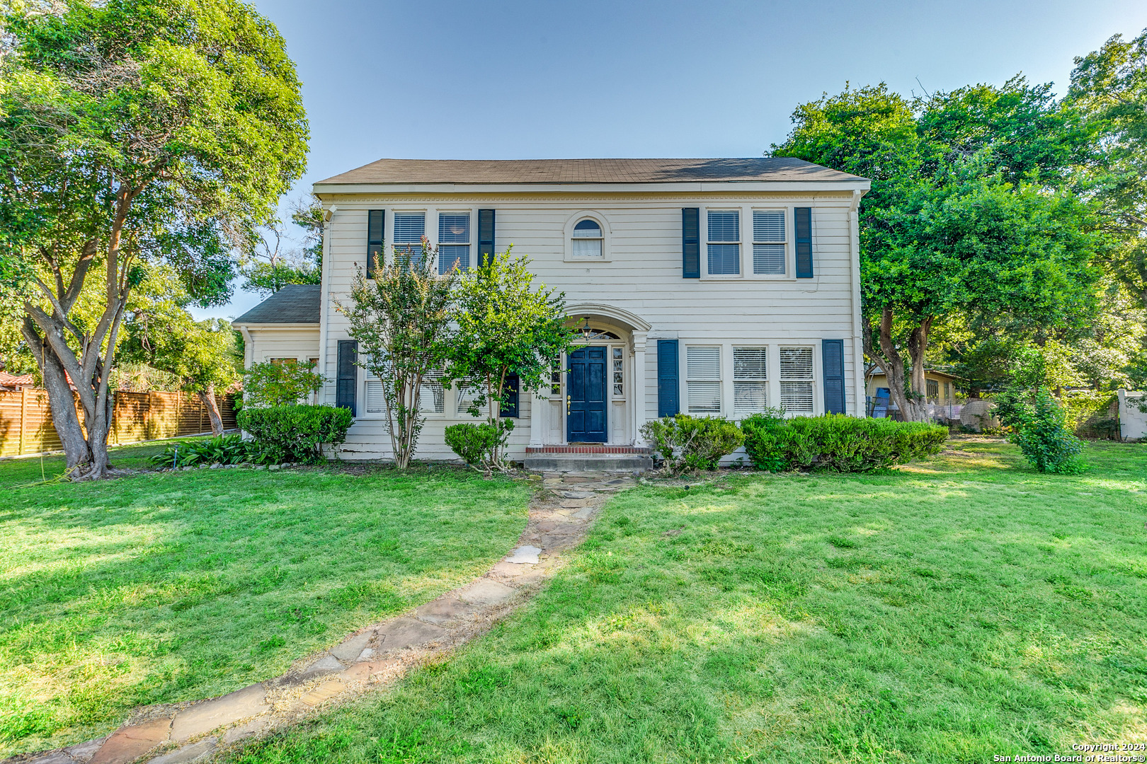 a front view of a house with a yard and trees