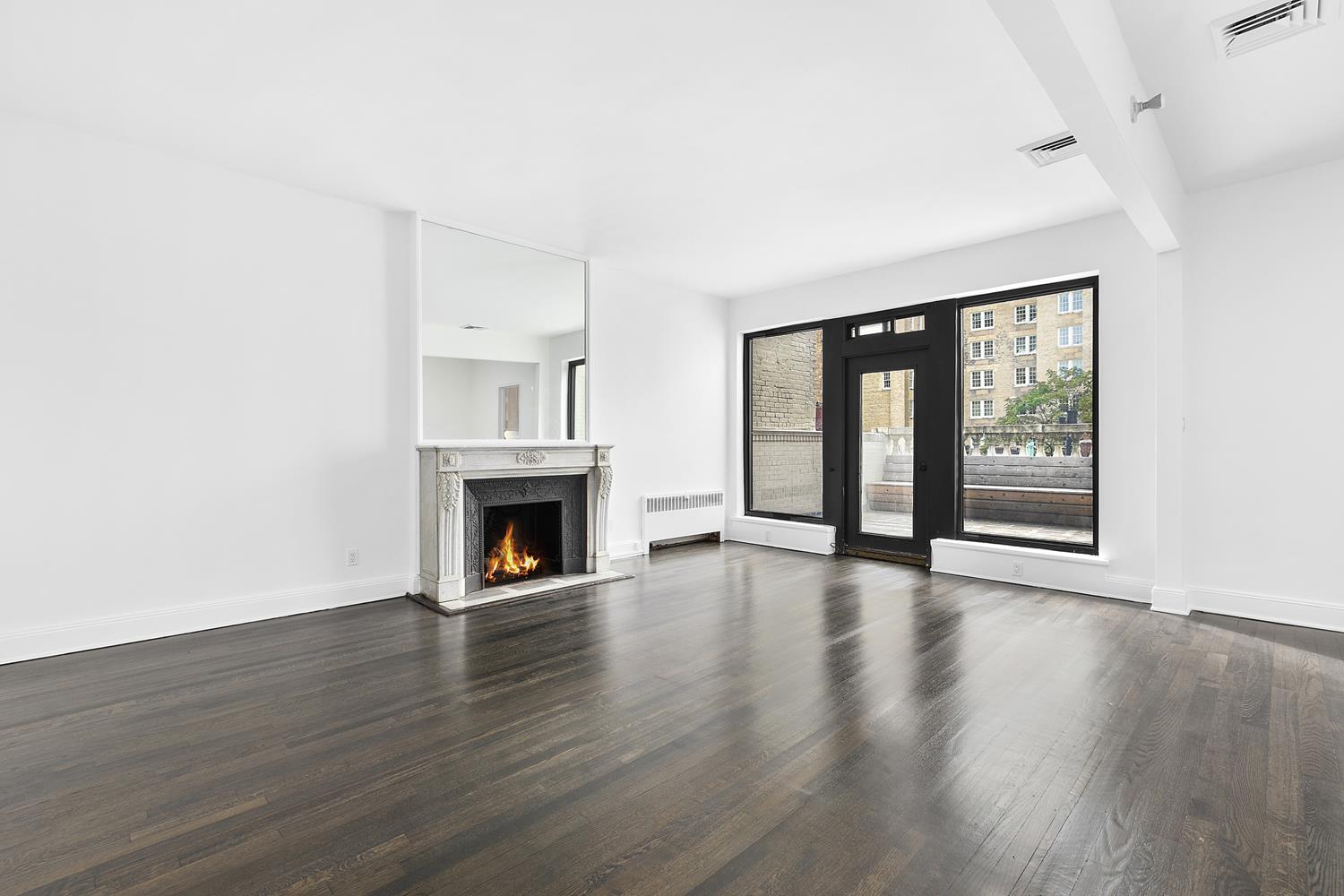 a view of an empty room with a fireplace and wooden floor