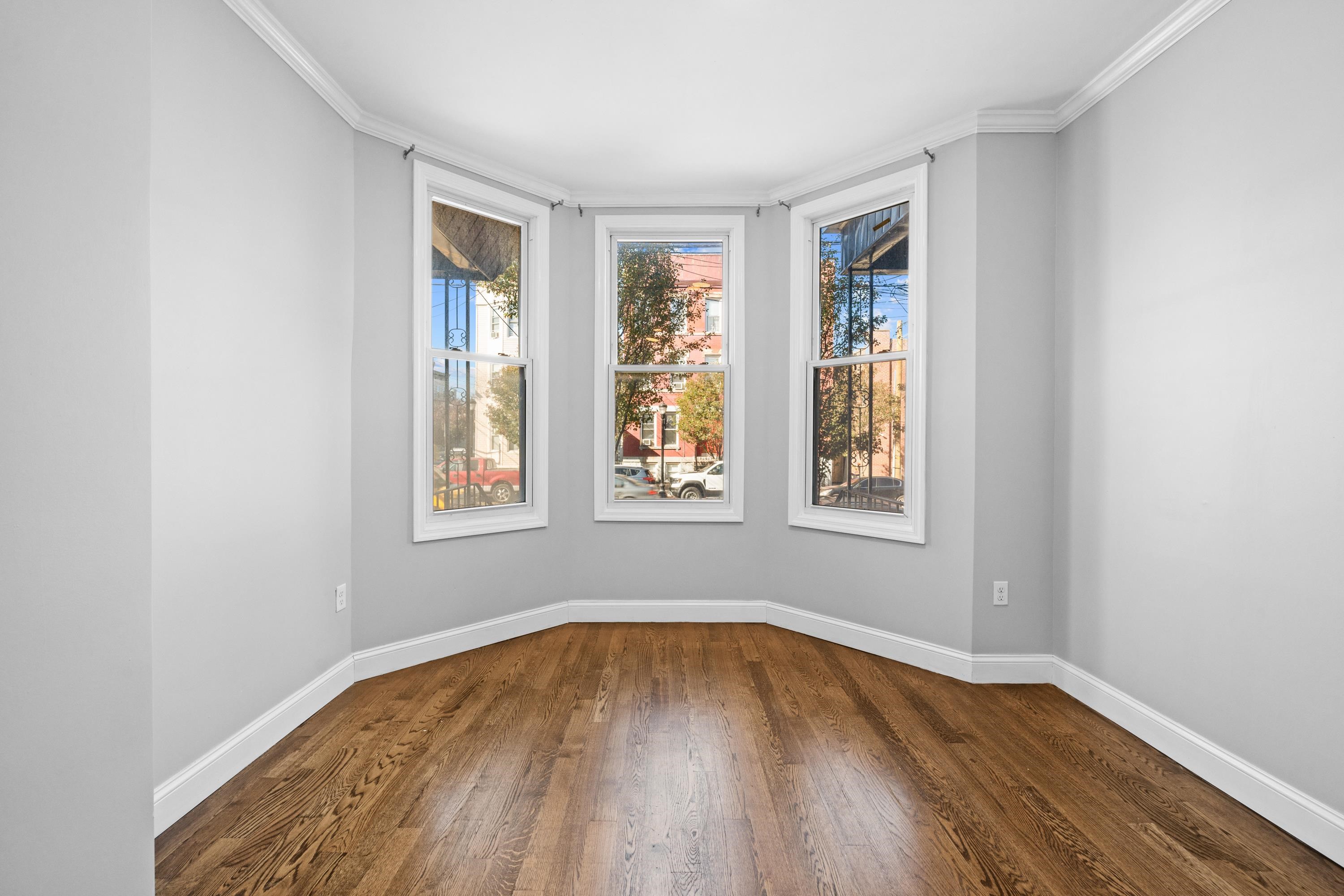 a view of empty room with wooden floor and fan