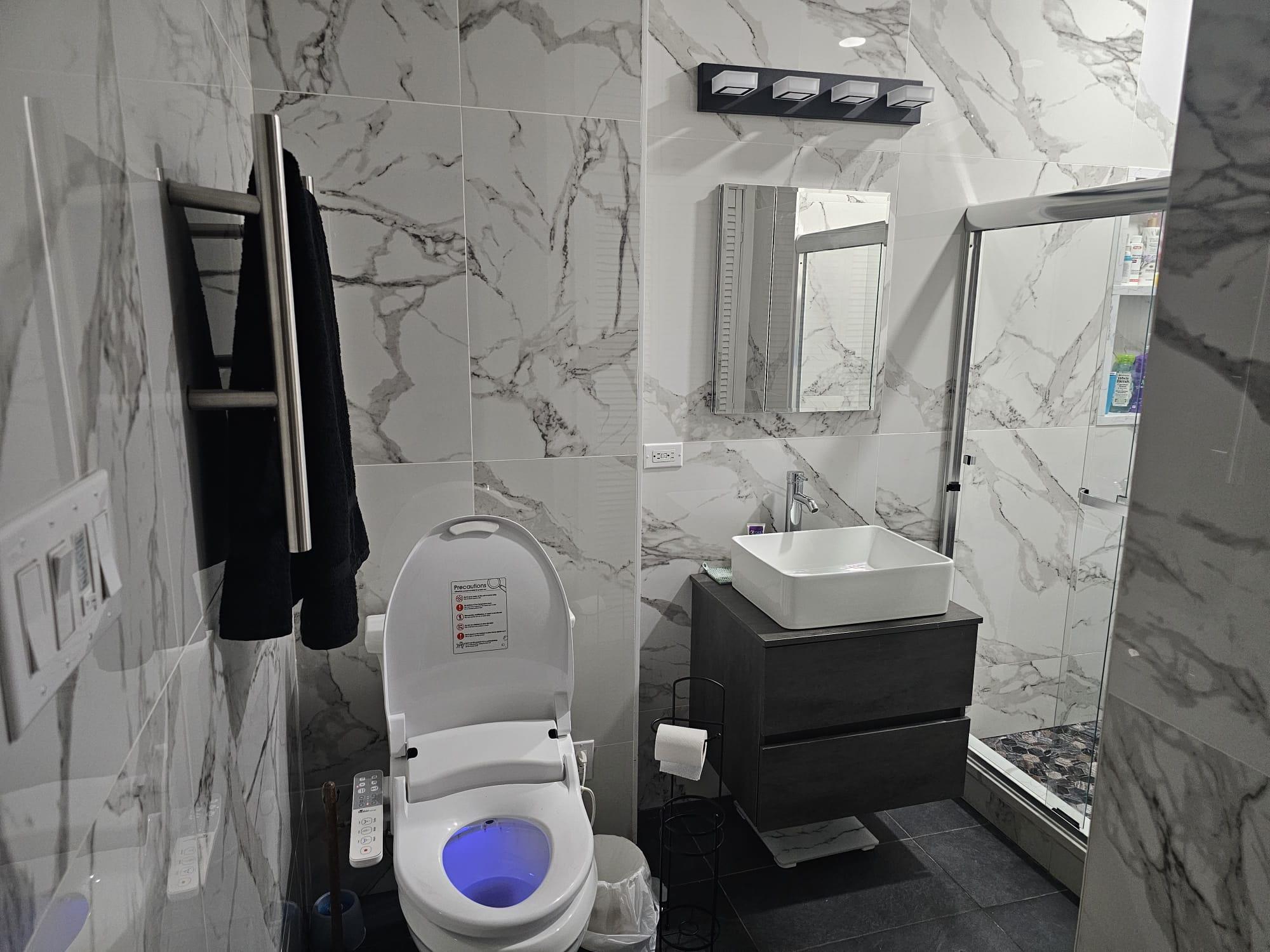 Bathroom featuring vanity, tile patterned floors, toilet, tile walls, and a shower with shower door