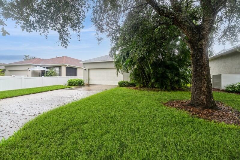 a view of house in front of a big yard with large trees