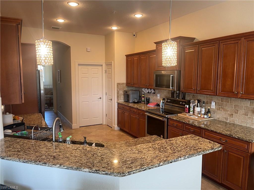 a kitchen with kitchen island granite countertop a sink stove and refrigerator