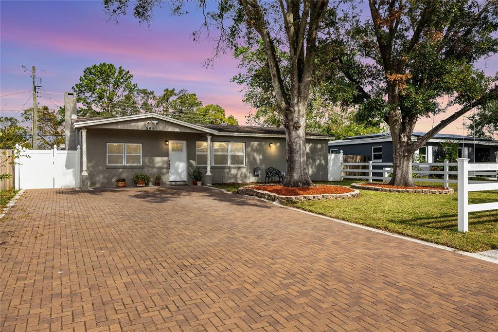 a front view of a house with a yard and large tree