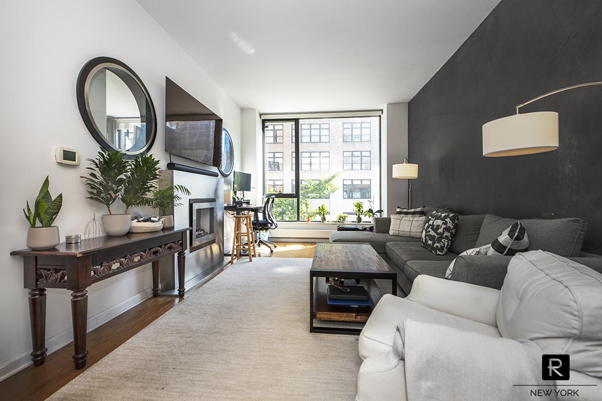 a living room with furniture and a large mirror next to a window