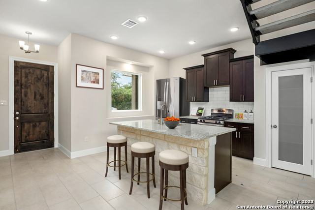 a kitchen with stainless steel appliances granite countertop a stove a sink a refrigerator and a refrigerator