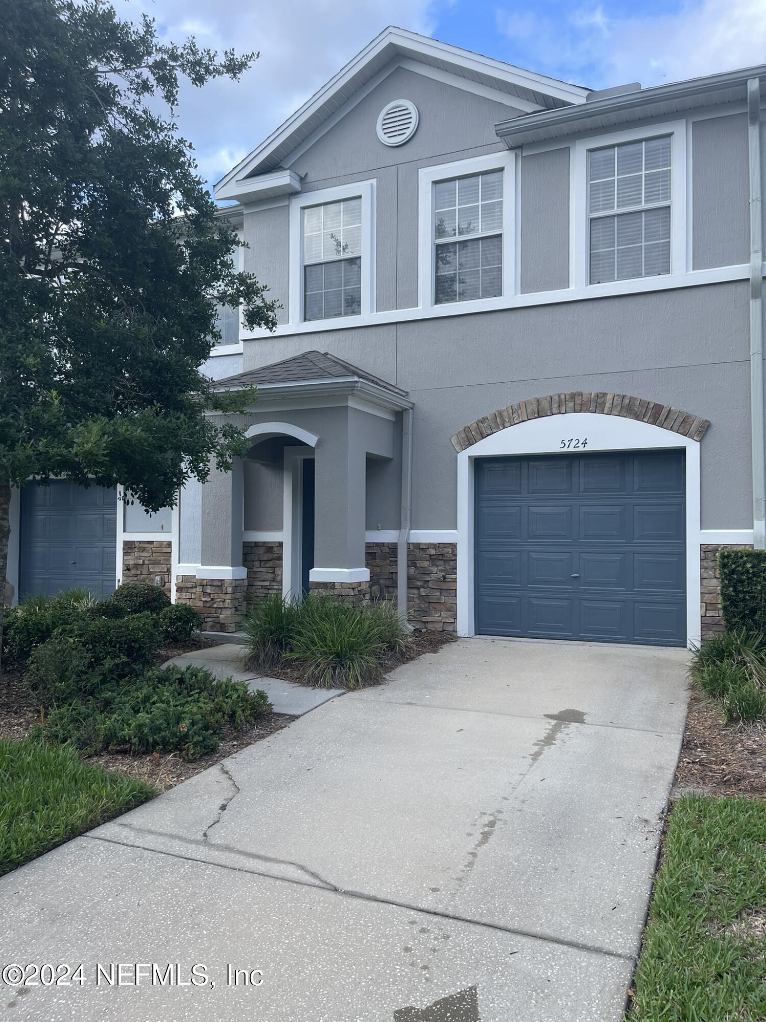 a front view of a house with yard and parking