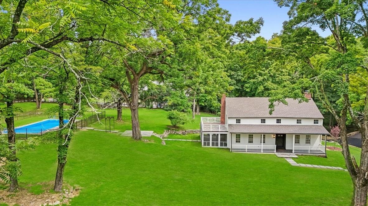 Country-style home featuring a porch and a front lawn