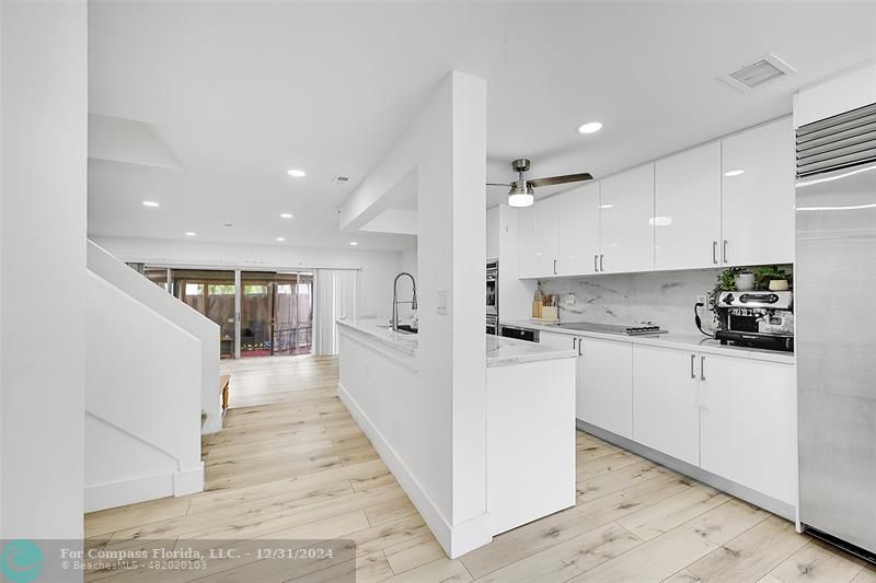 a large white kitchen with kitchen island a sink a stove a refrigerator and white cabinets next to a window