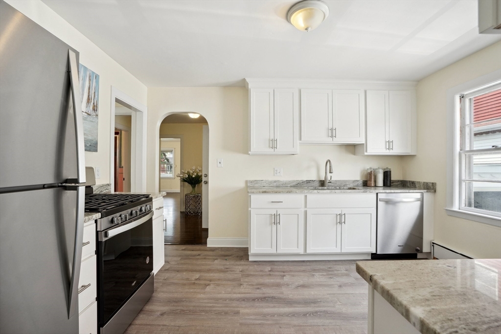 a kitchen with granite countertop a stove a sink and a refrigerator