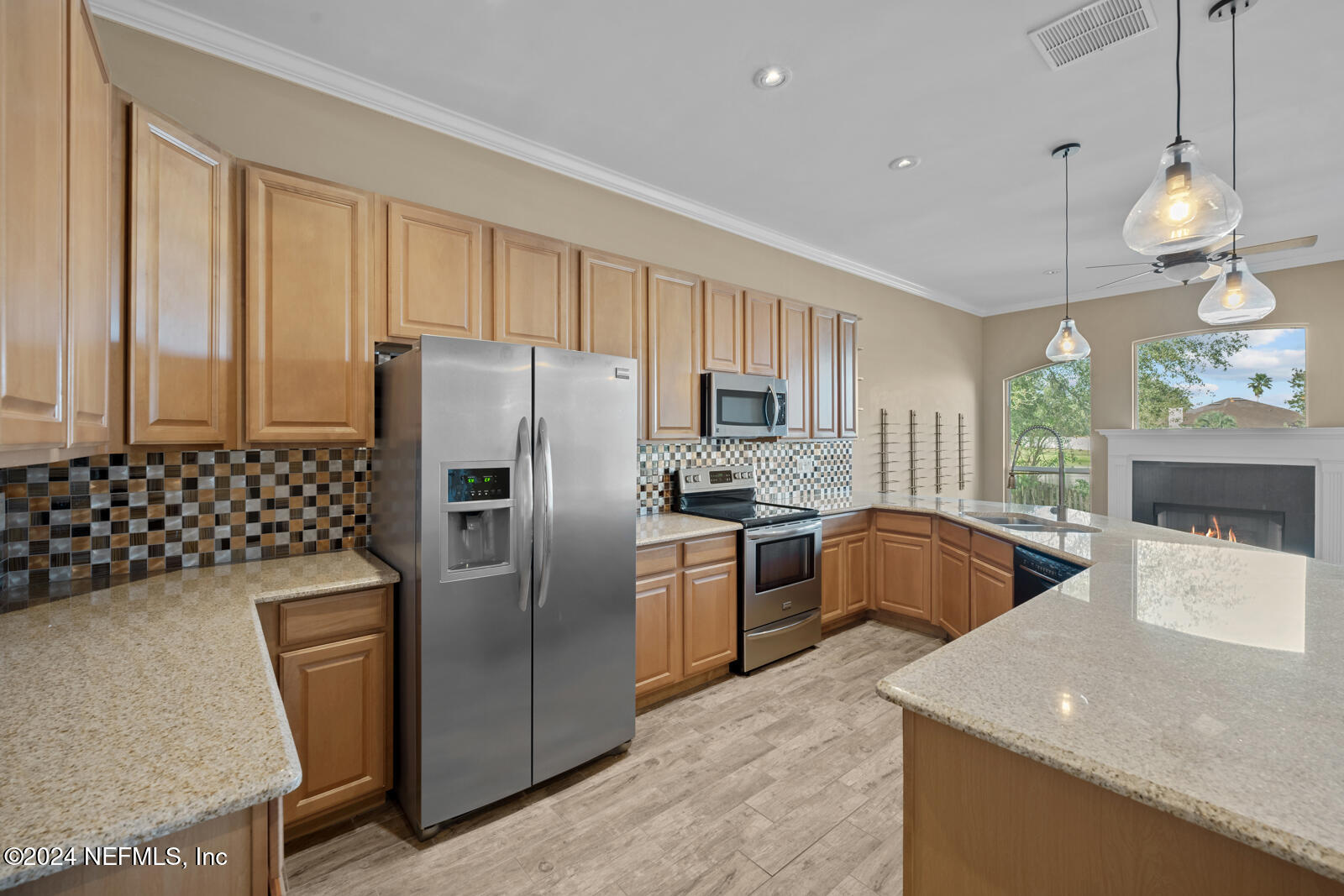 a kitchen with stainless steel appliances granite countertop a sink a stove a refrigerator a washer dryer and a dining table