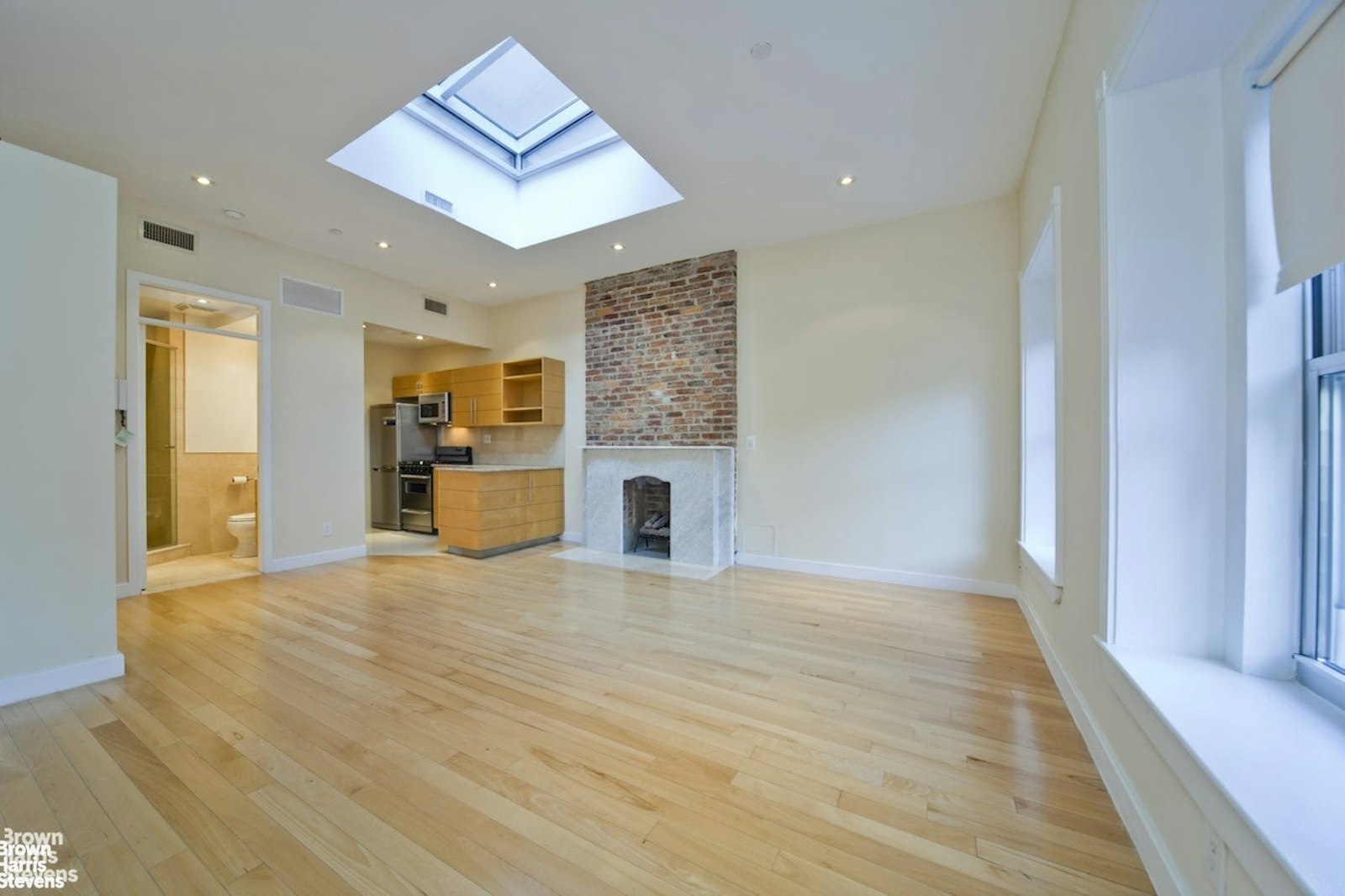 a view of an empty room with a fireplace and a window