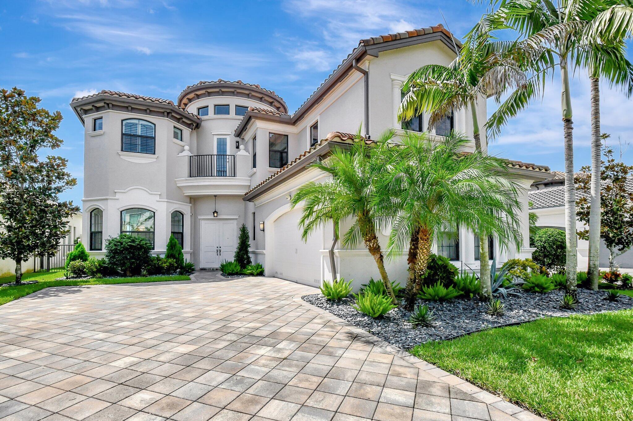 a front view of a house with a yard and palm trees